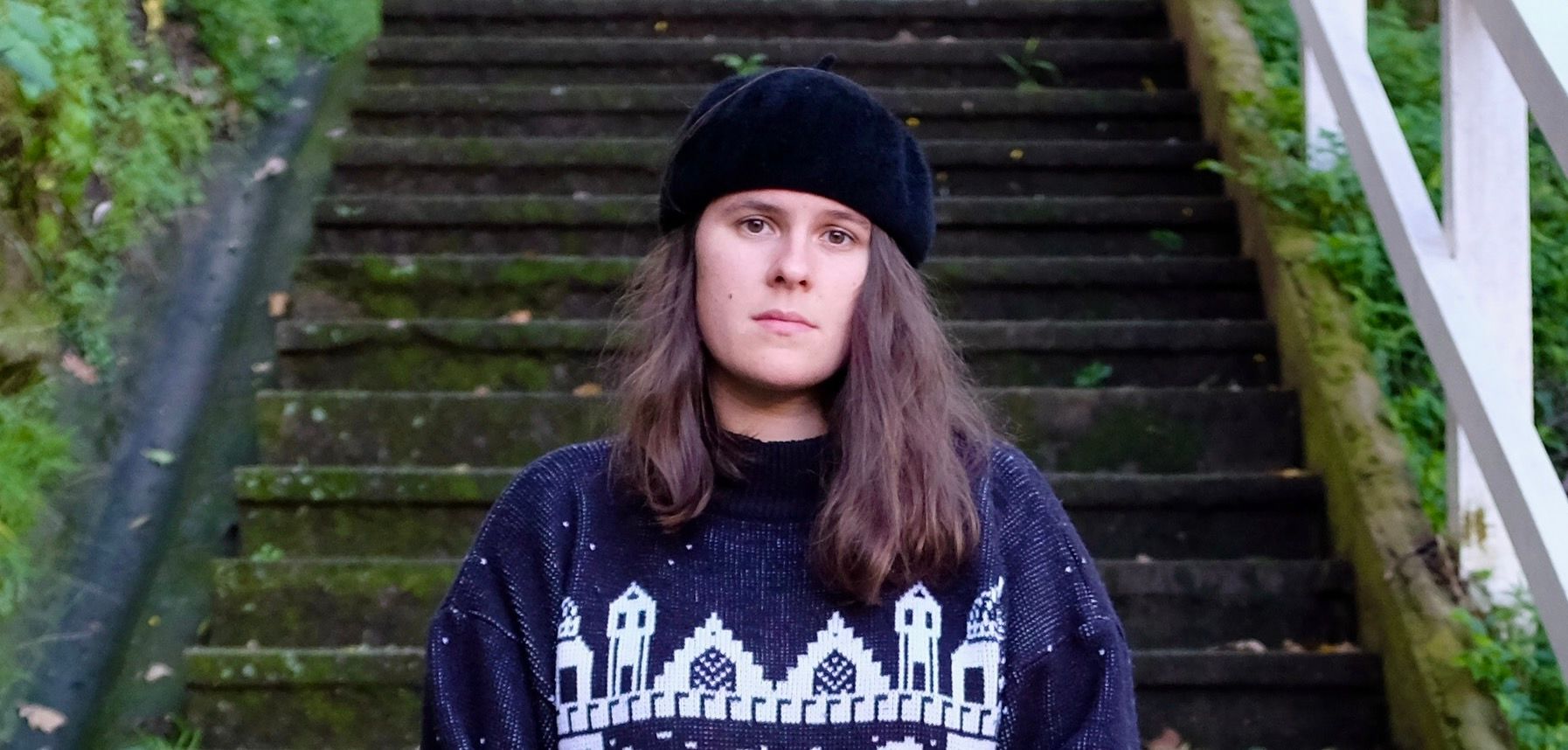 Evangelina Telfar’s headshot. They have shoulder length hair, with a beret and are wearing a jumper.